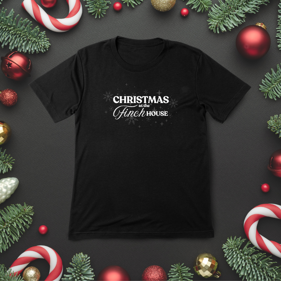 Black t-shirt with 'Christmas at the Finch House' text surrounded by Christmas decorations on a dark background